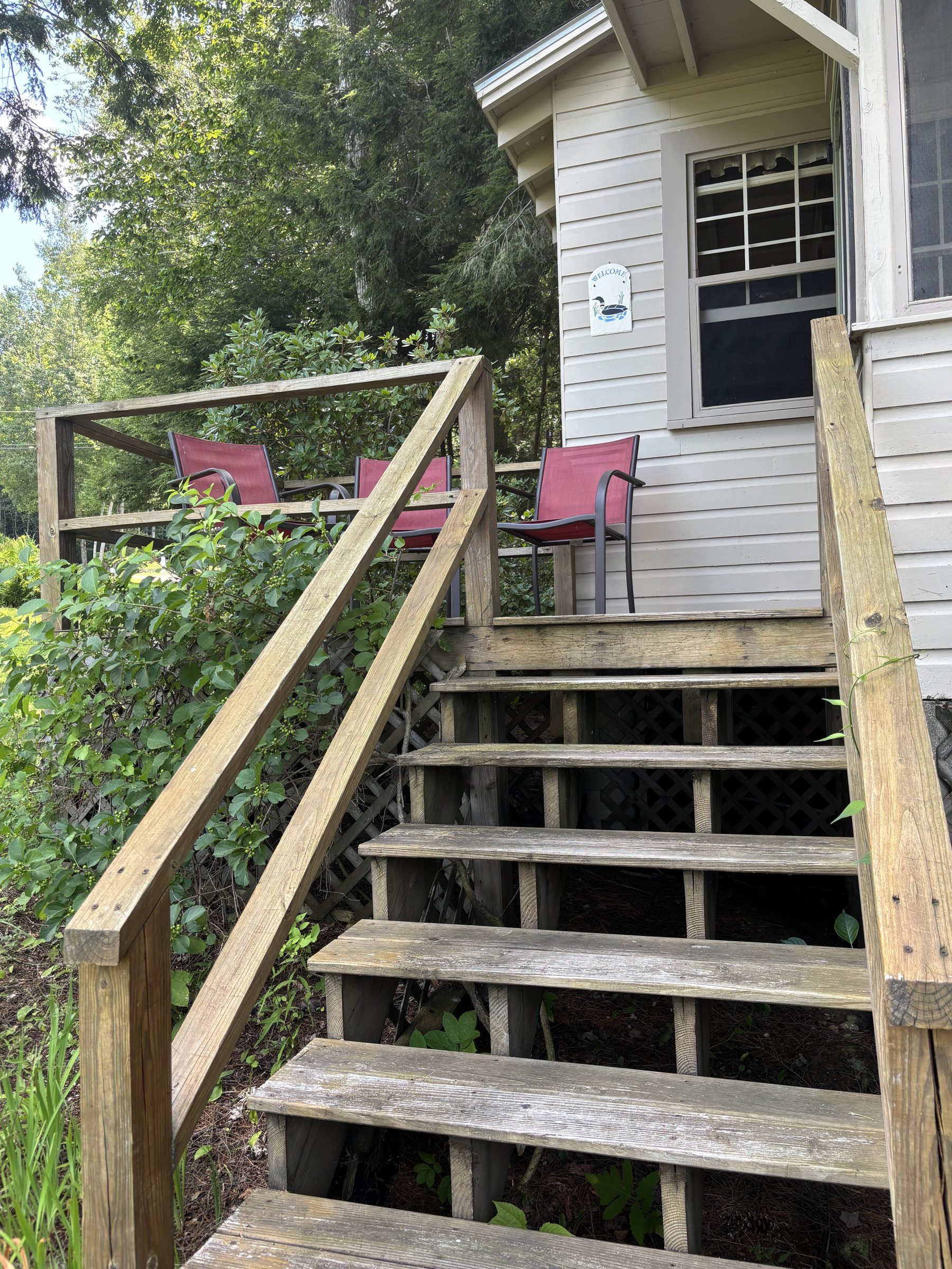 Deck stairs with red chairs and a welcome sign