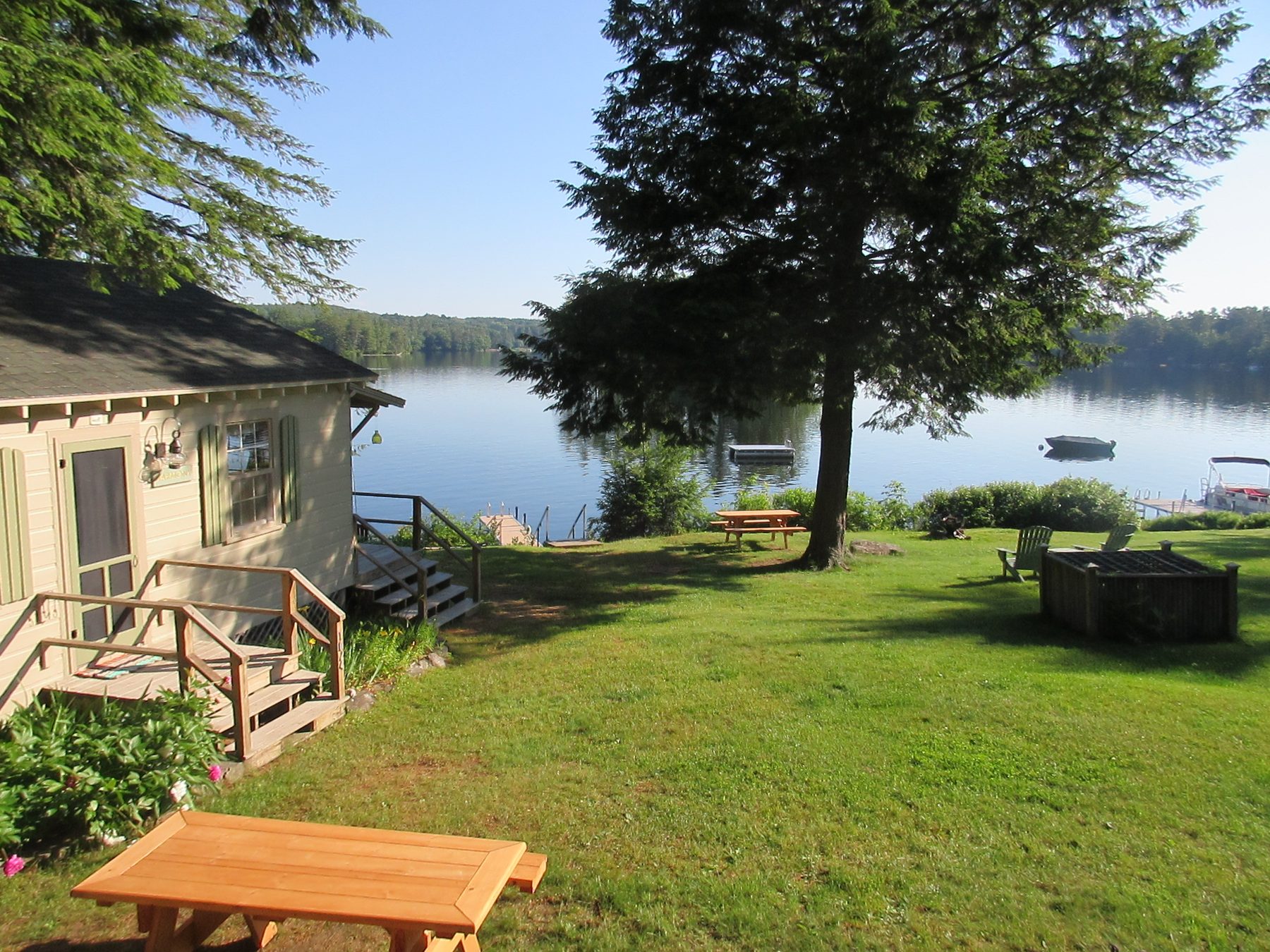 Cabin exterior with picnic tables and fire pit by the lake